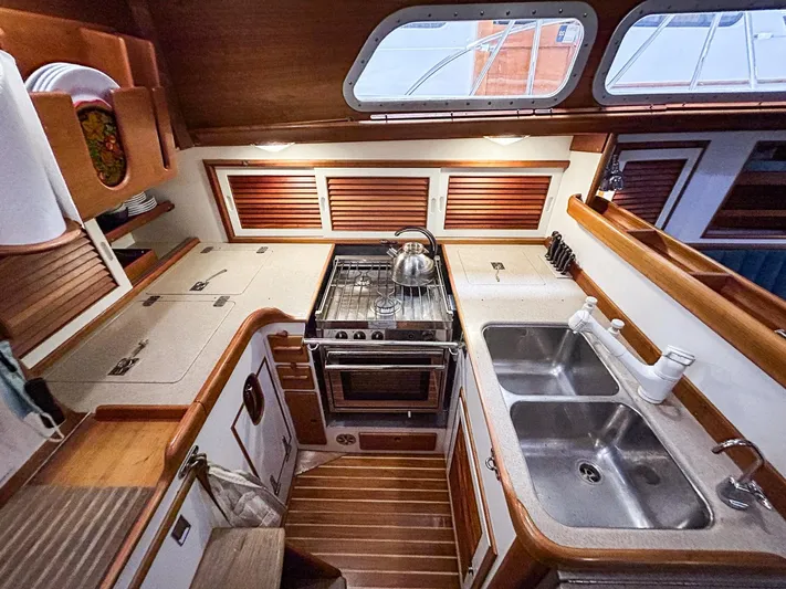 Golden Eye Yacht Photos Pics Hinckley Sou'wester 42 MKII 1996 yacht kitchen with stove, sink, and wooden cabinetry.