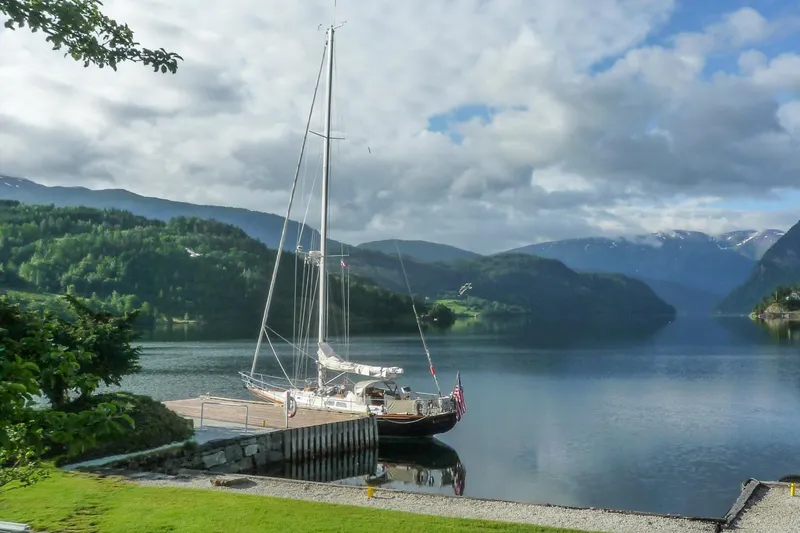 Golden Eye Yacht Photos Pics Sailboat Hinckley Sou'wester 42 MKII (1996) docked by a serene lake with mountainous backdrop.