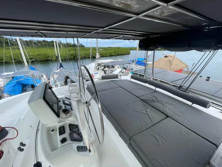 Matilda Mia Yacht Photos Pics 2015 Lagoon 52 yacht helm with cushioned seating, docked near lush greenery.