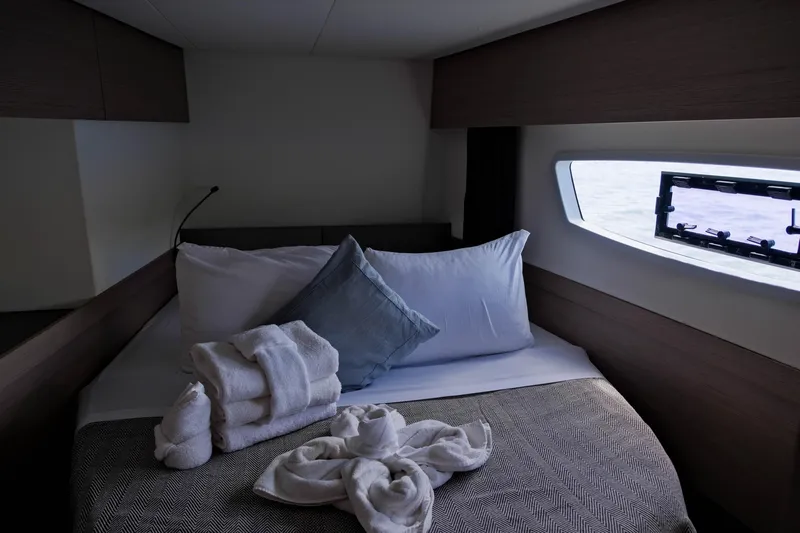 Ruckus Yacht Photos Pics Cozy cabin interior of 2021 Fountaine Pajot Elba 45 Catamaran with bed and window view.
