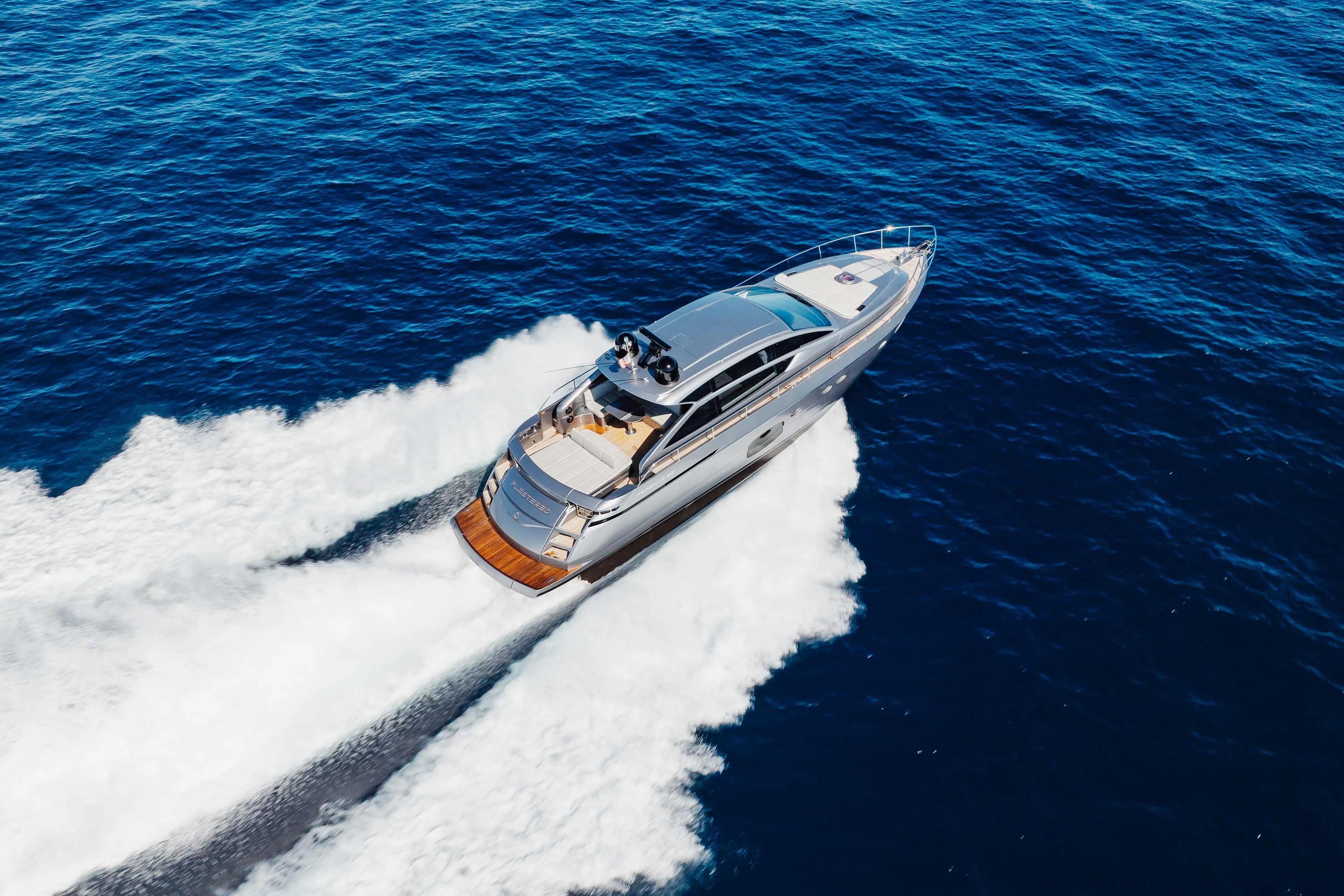 2016 Pershing 62 yacht cruising on open blue sea, aerial view.