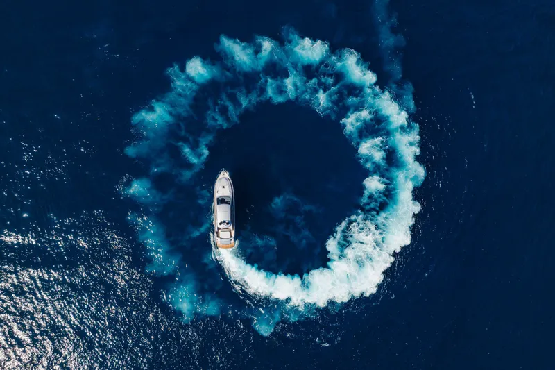 Plastered Yacht Photos Pics Aerial view of 2016 Pershing 62 yacht creating circular wake in deep blue ocean.