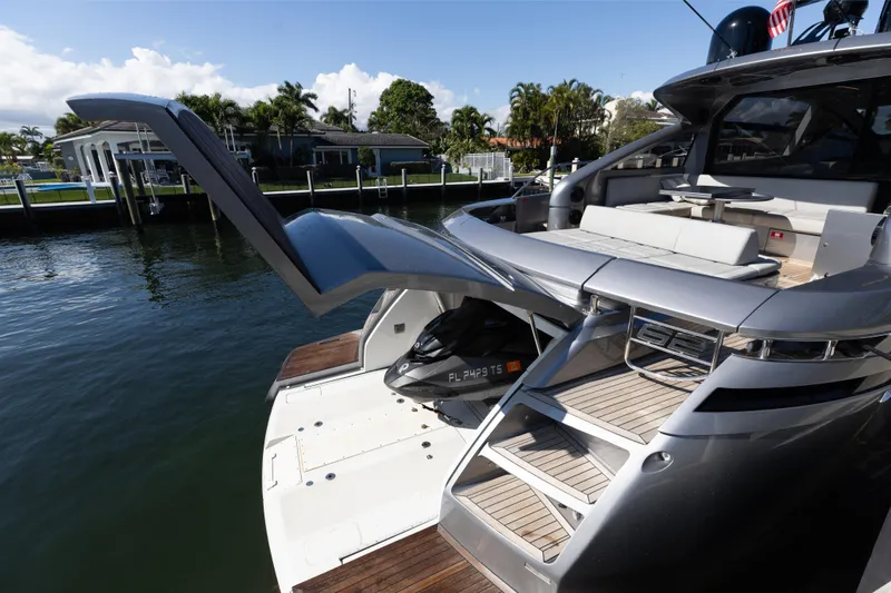 Plastered Yacht Photos Pics 2016 Pershing 62 yacht with open garage and sleek design, docked by waterfront homes.