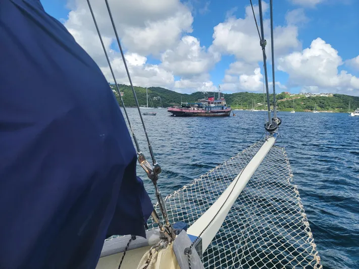 Maisie Rose Yacht Photos Pics Sailboat view of a harbor with a distant ship, under a blue sky.