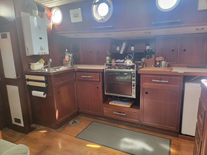 Maisie Rose Yacht Photos Pics Vintage 1984 Kuipper NV Holland boat kitchen with wooden cabinets and porthole windows.