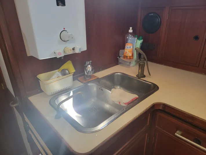 Maisie Rose Yacht Photos Pics Vintage 1984 Kuipper NV Holland kitchen sink with wooden cabinetry and cleaning supplies.