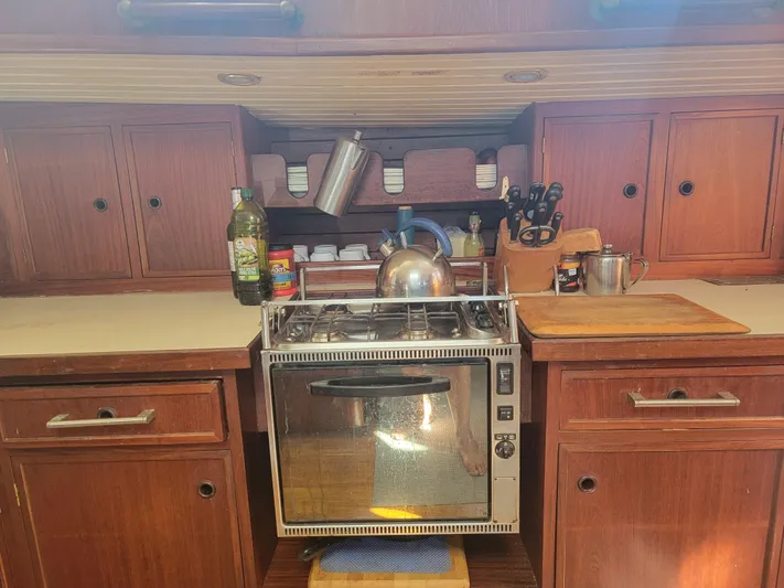 Maisie Rose Yacht Photos Pics Vintage 1984 Kuipper NV Holland boat kitchen with stove, wooden cabinets, and cooking essentials.