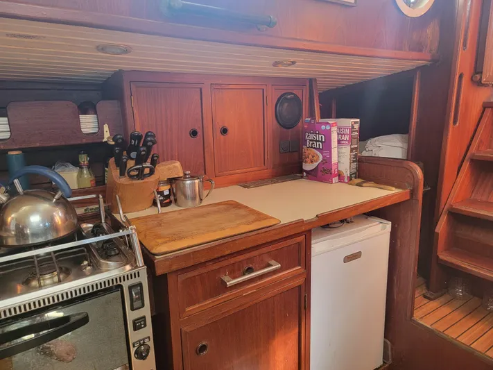 Maisie Rose Yacht Photos Pics Compact wooden boat kitchen with stove, cutting board, and storage, 1984 Kuipper NV Holland model.