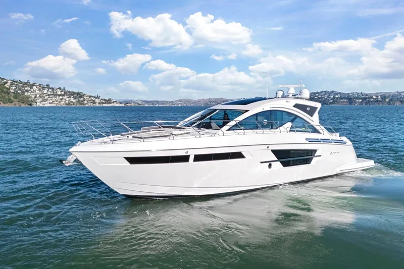 Simply Complicated Yacht Photos Pics 2019 Cruisers Yachts 54 Cantius cruising on a sunny day, scenic coastal backdrop.