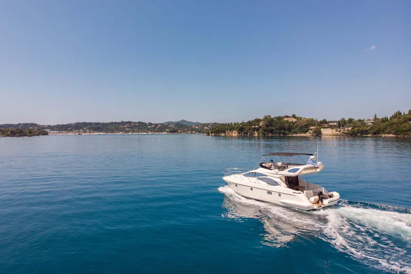 Shine IV Yacht Photos Pics 2006 Azimut 43 yacht cruising on serene blue waters near a scenic coastline.