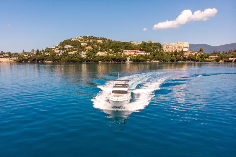 Shine IV Yacht Photos Pics Azimut 43 yacht cruising on clear blue water near a scenic coastal landscape, 2006 model.