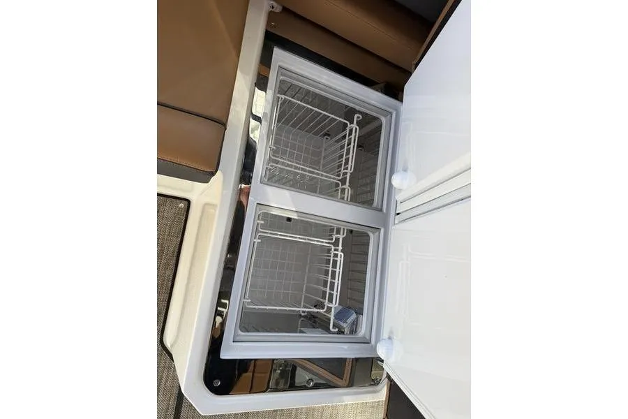 Open storage compartment in 2025 Cobalt R35 boat with wire baskets.