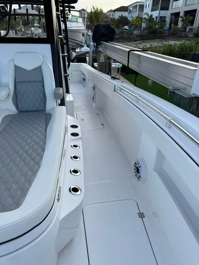  Yacht Photos Pics 2023 Invincible 33 Catamaran deck with seating and rod holders, docked near waterfront homes.