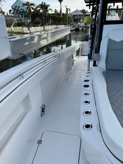  Yacht Photos Pics 2023 Invincible 33 Catamaran boat interior with seating and rod holders, docked by a canal.