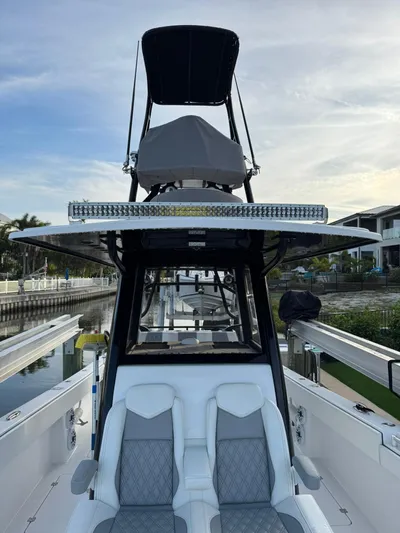  Yacht Photos Pics 2023 Invincible 33 Catamaran with dual seating and elevated helm station, docked by waterfront homes.