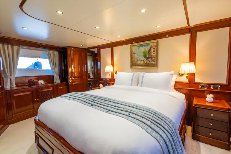 Stella Fiera Yacht Photos Pics Luxurious bedroom interior on a 1998 Benetti Classic yacht, featuring elegant wood finishes and cozy lighting.