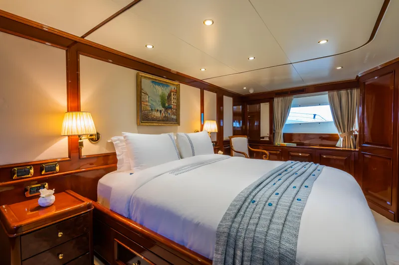 Stella Fiera Yacht Photos Pics Luxurious bedroom interior on a 1998 Benetti Classic yacht, featuring elegant wood paneling and cozy lighting.
