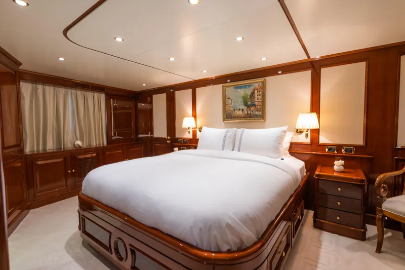 Stella Fiera Yacht Photos Pics Luxurious bedroom interior of 1998 Benetti Classic yacht with elegant wood paneling and cozy lighting.