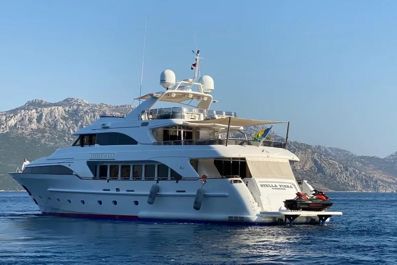 Stella Fiera Yacht Photos Pics Luxurious 1998 Benetti Classic yacht on serene waters with mountainous backdrop.