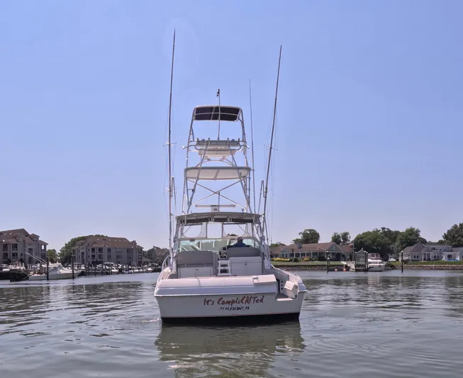  Yacht Photos Pics 2004 Stamas 370 Express boat on calm water, clear sky, residential backdrop.