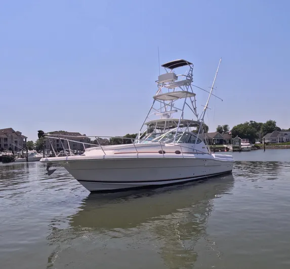  Yacht Photos Pics 2004 Stamas 370 Express boat on calm water, clear sky, residential backdrop.