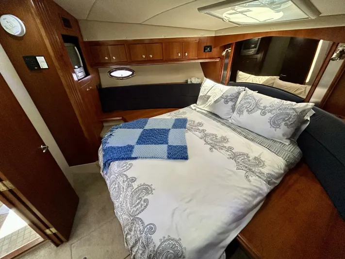  Yacht Photos Pics Luxurious 2005 Cruisers Yachts 455 Express Motor Yacht bedroom with elegant bedding and wood cabinetry.
