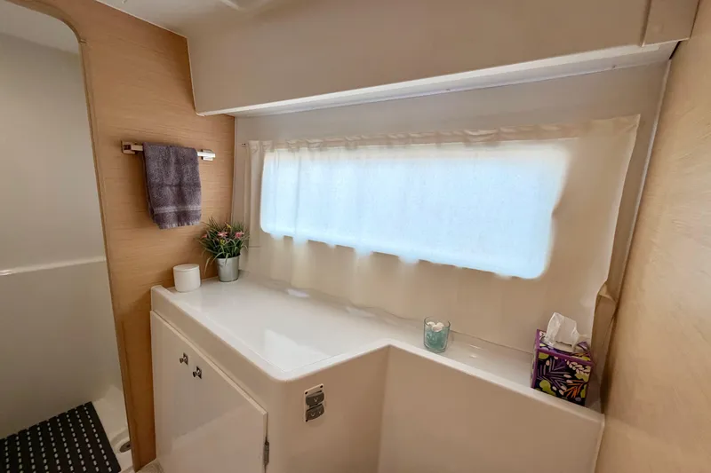 Island Hopp'r Owners Version Yacht Photos Pics Bathroom interior of 2017 Lagoon 42 catamaran with window, towel, and decor.