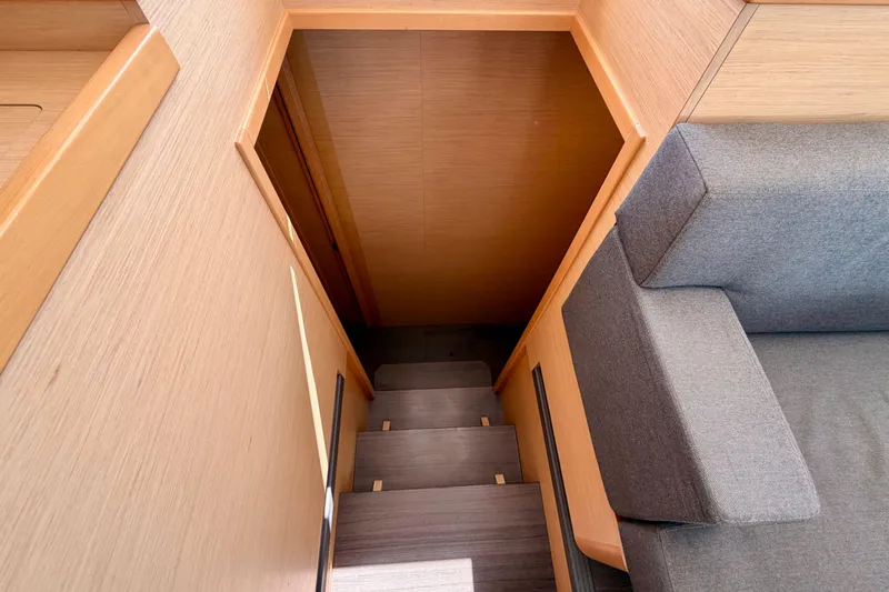 Island Hopp'r Owners Version Yacht Photos Pics Interior stairs of 2017 Lagoon 42 yacht, featuring wooden finish and gray sofa.