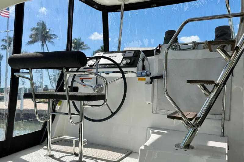 Island Hopp'r Owners Version Yacht Photos Pics Helm of 2017 Lagoon 42 catamaran with steering wheel and control panel, tropical backdrop.