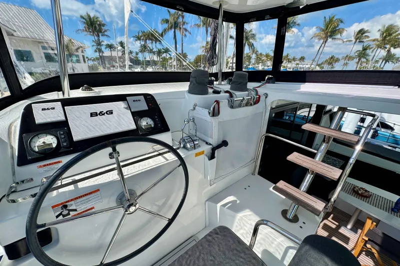 Island Hopp'r Owners Version Yacht Photos Pics 2017 Lagoon 42 yacht cockpit with steering wheel, navigation system, and tropical backdrop.