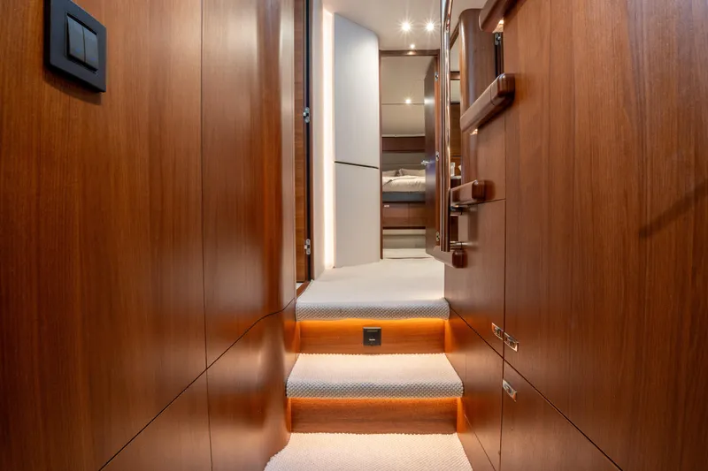  Yacht Photos Pics Luxurious interior of 2020 Princess S66 yacht with wooden finishes and carpeted stairs.