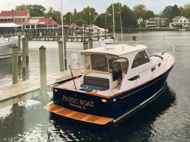  Yacht Photos Pics 2003 Legacy Yachts 34 Sedan docked at a marina, surrounded by calm water and scenic buildings.