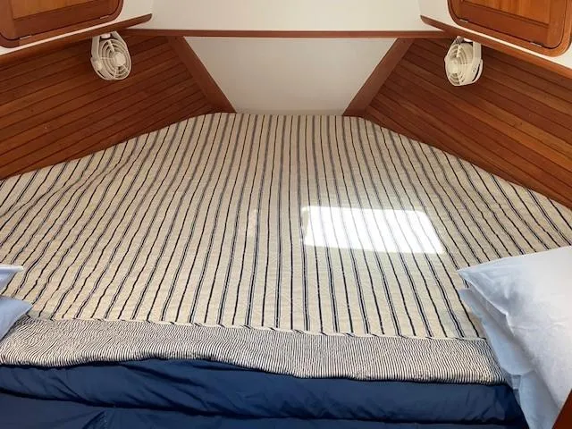  Yacht Photos Pics Cozy cabin bed in 2003 Legacy Yachts 34 Sedan with striped bedding and wooden accents.