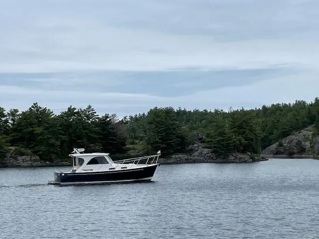  Yacht Photos Pics 2003 Legacy Yachts 34 Sedan cruising on a serene lake with forested shoreline.