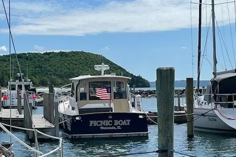  Yacht Photos Pics 2003 Legacy Yachts 34 Sedan docked, displaying an American flag, with scenic background.