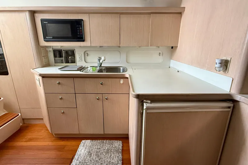  Yacht Photos Pics 1994 Tiara Yachts 4000 Express kitchen with microwave, sink, and wooden cabinetry.
