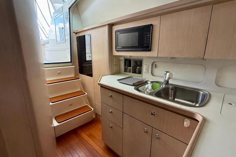  Yacht Photos Pics 1994 Tiara Yachts 4000 Express interior with kitchenette, sink, microwave, and wooden stairs.