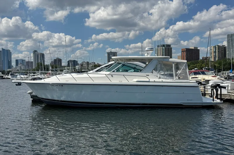  Yacht Photos Pics 1994 Tiara Yachts 4000 Express docked in a marina with city skyline background.