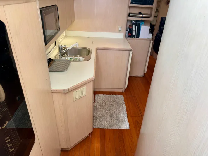  Yacht Photos Pics 2004 Tiara Yachts 4000 Express interior kitchen with sink, microwave, and wooden flooring.