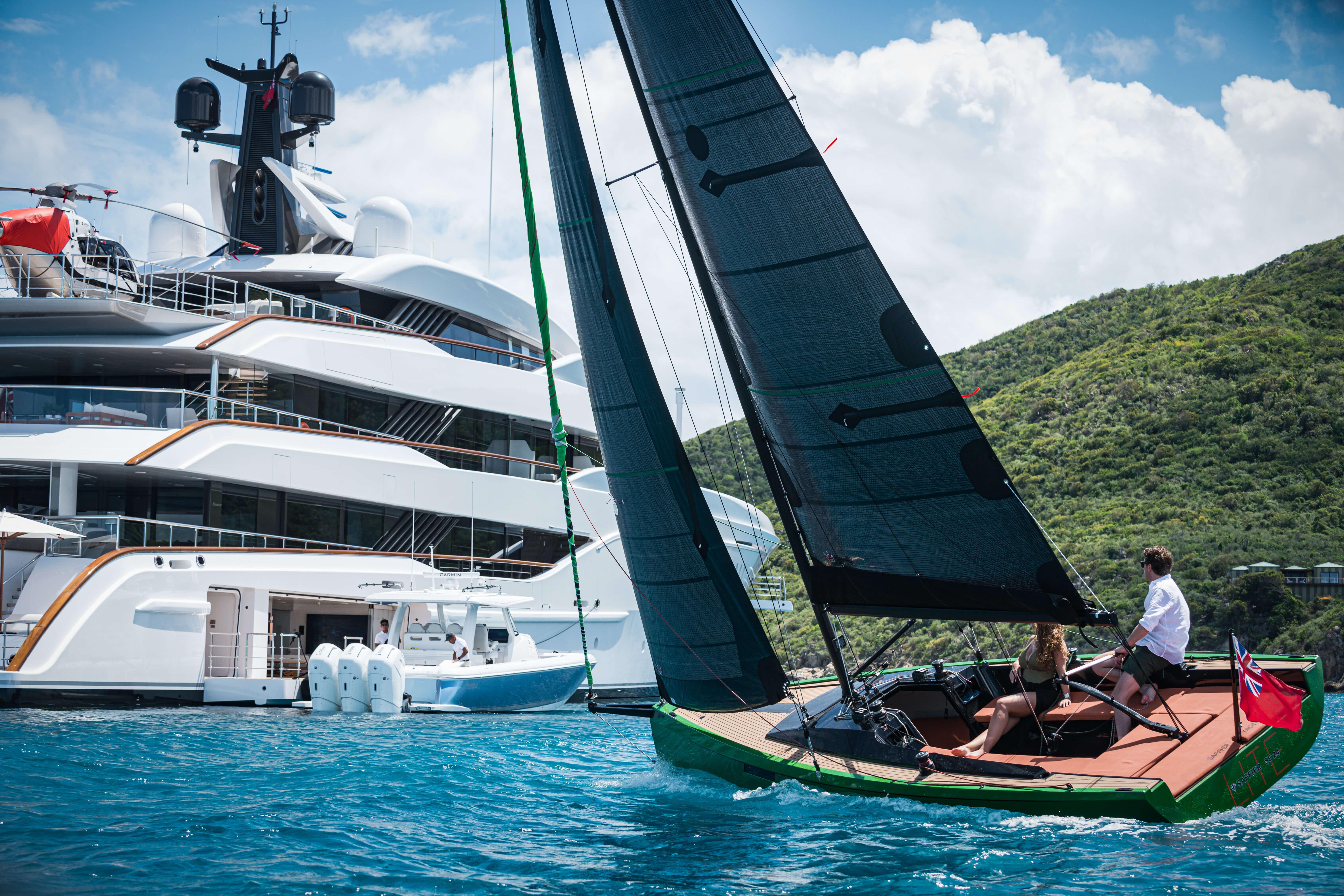 Saffier SE24 Lite sailboat cruising near a luxury yacht, 2026 model, in scenic waters.