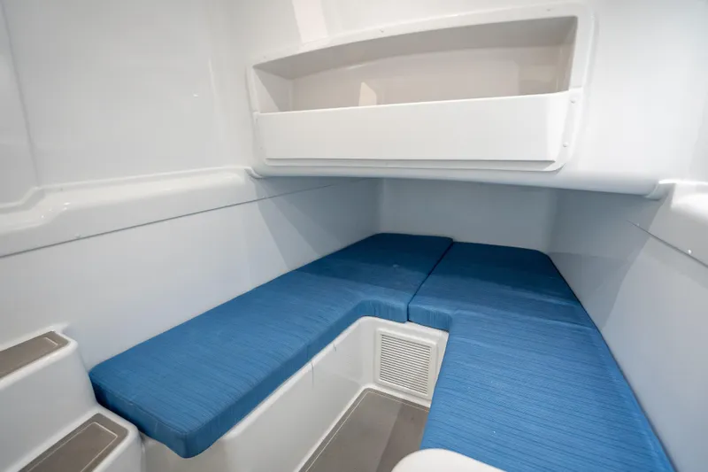 New Stock 42 Offshore Yacht Photos Pics 2026 Yellowfin 42 Offshore cabin interior with blue seating and white storage shelf.