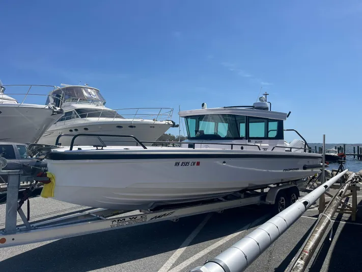  Yacht Photos Pics 2022 Axopar 28 CABIN boat on trailer, docked under clear blue sky.