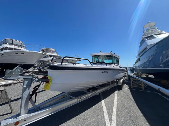  Yacht Photos Pics 2022 Axopar 28 CABIN boat on trailer, parked between other boats under clear blue sky.