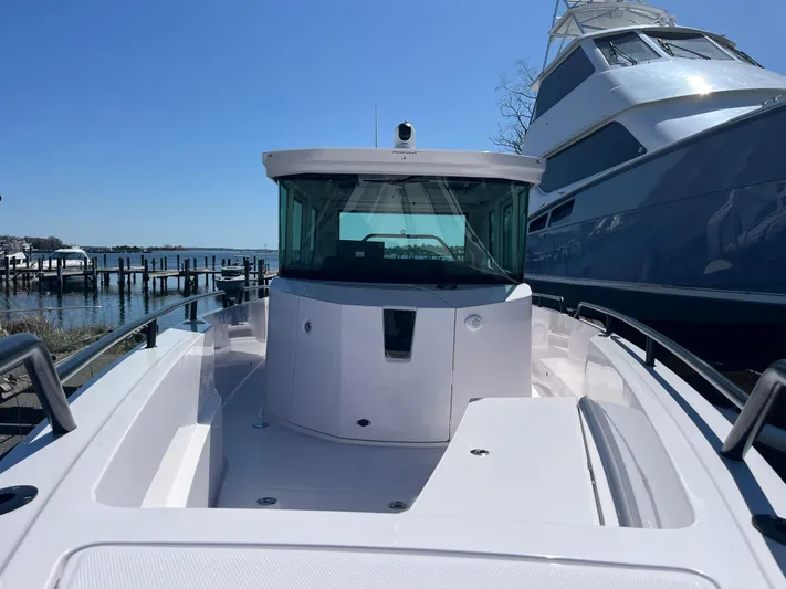  Yacht Photos Pics 2022 Axopar 28 CABIN boat docked near a marina under clear blue skies.