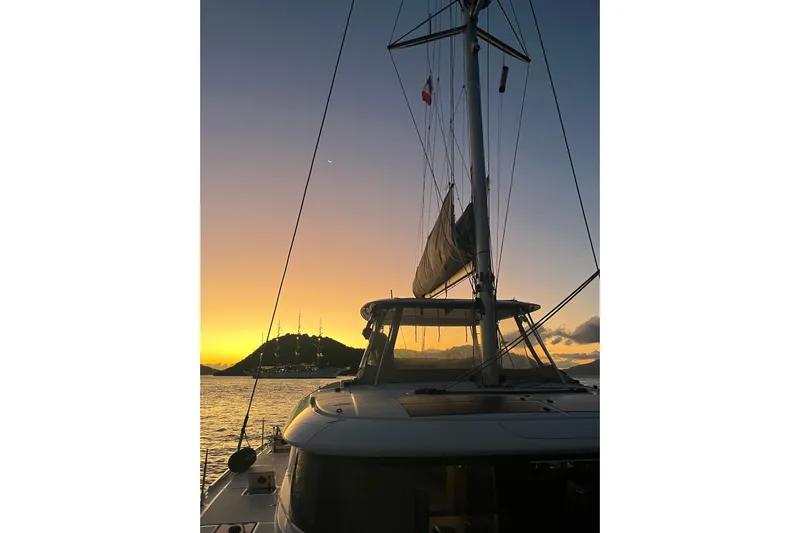  Yacht Photos Pics Lagoon 46 catamaran at sunset, 2022 model, with scenic ocean and island view.