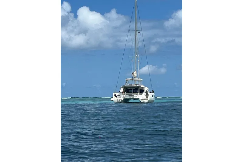  Yacht Photos Pics 2022 Lagoon 46 catamaran sailing on clear blue ocean under a bright sky.