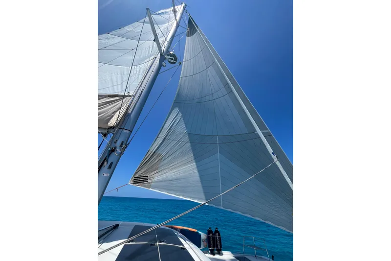  Yacht Photos Pics Sailing on a 2022 Lagoon 46 catamaran with full sails against a clear blue sky.