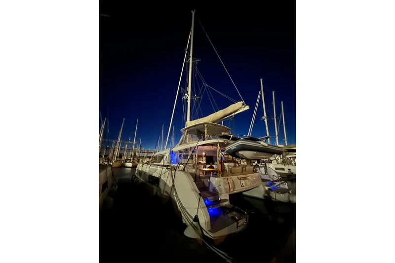  Yacht Photos Pics 2022 Lagoon 46 catamaran docked at night with illuminated deck and sails.