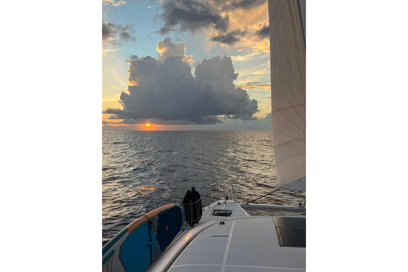  Yacht Photos Pics Lagoon 46 sailing at sunset, 2022 model, with dramatic clouds over the ocean.