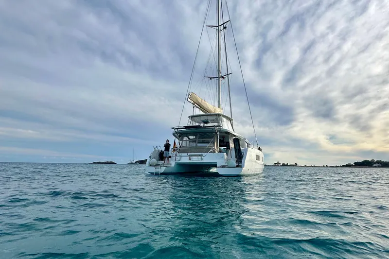  Yacht Photos Pics 2022 Lagoon 46 catamaran sailing on calm ocean waters under a cloudy sky.